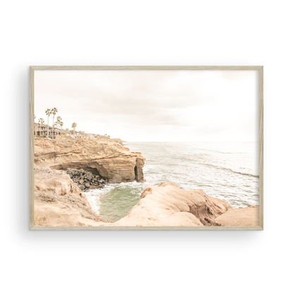 Fine art of Sunset Cliffs, San Diego California horizontal print of hazy high-angle landscape beach photography captures a light blue ocean meeting tall tan, rocky, brown cliffs rise as iconic coastal scenery. Photograph in minimalist mock up.