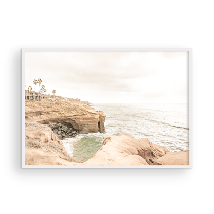 Fine art of Sunset Cliffs, San Diego California horizontal print of hazy high-angle landscape beach photography captures a light blue ocean meeting tall tan, rocky, brown cliffs rise as iconic coastal scenery. Photograph in minimalist mock up.