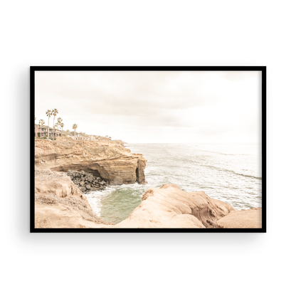 Fine art of Sunset Cliffs, San Diego California horizontal print of hazy high-angle landscape beach photography captures a light blue ocean meeting tall tan, rocky, brown cliffs rise as iconic coastal scenery. Photograph in minimalist mock up.