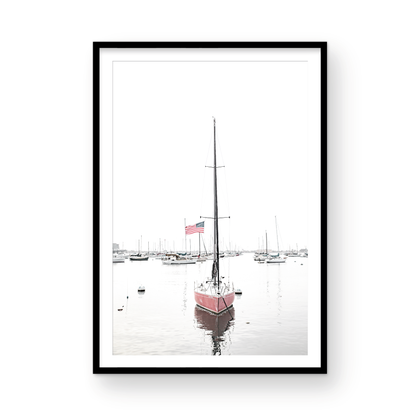 A vertical San Diego print featuring a lone red sailboat with an American flag, anchored in a calm San Diego harbor. This minimalist ocean print captures the essence of coastal photography and is perfect for modern coastal decor. Photograph in minimalist mock up.