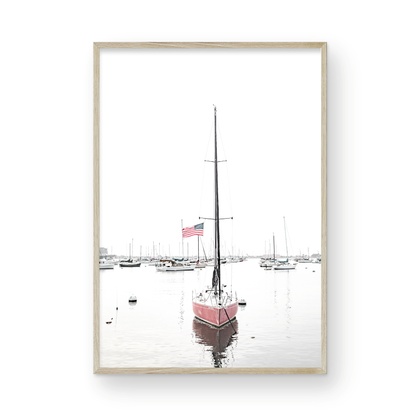 A vertical San Diego print featuring a lone red sailboat with an American flag, anchored in a calm San Diego harbor. This minimalist ocean print captures the essence of coastal photography and is perfect for modern coastal decor. Photograph in minimalist mock up.