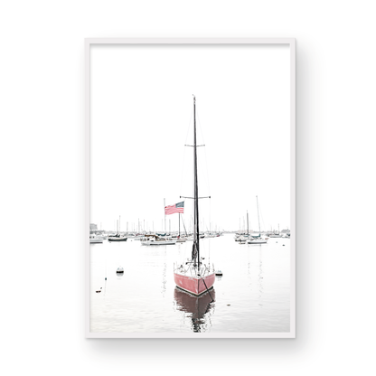A vertical San Diego print featuring a lone red sailboat with an American flag, anchored in a calm San Diego harbor. This minimalist ocean print captures the essence of coastal photography and is perfect for modern coastal decor. Photograph in minimalist mock up.