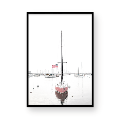 A vertical San Diego print featuring a lone red sailboat with an American flag, anchored in a calm San Diego harbor. This minimalist ocean print captures the essence of coastal photography and is perfect for modern coastal decor. Photograph in minimalist mock up.