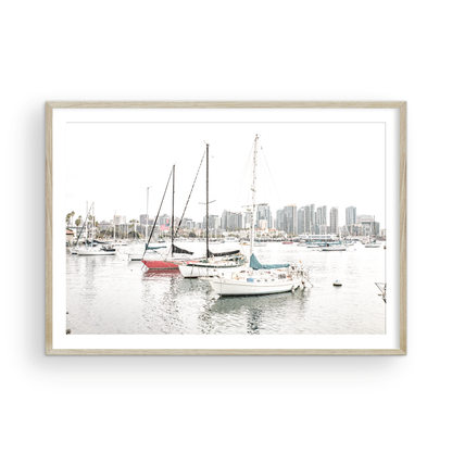 A horizontal San Diego print showcasing numerous sailboats in San Diego Harbor with the city skyline in the background. This modern coastal print embodies the Southern California coastal photography, perfect for a large beach wall art. Photograph in minimalist mock up.