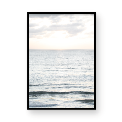 Fine art of vertical landscape print by Southern California photographer Kim Dybczak of Salt Creek Prints, featuring a bright image capturing pale blue ocean waves, light gray clouds in a bright sky. Gentle, small waves in the near and far distance. The sky is a uniform, pale white, creating a soft, overcast atmosphere. Photograph in framed minimalist mock up