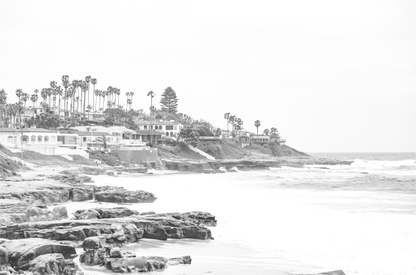 Fine art of WindanSea Beach, La Jolla California horizontal landscape black and white print by Southern California photographer Kim Dybczak of Salt Creek Prints, featuring a powerful waves crashing against the rocky shore of California coast. Beach homes and palm trees sit atop the cliffside, with stairs leading down to a sheltered area.