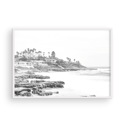 Fine art of WindanSea Beach, La Jolla California horizontal landscape black and white print by Southern California photographer Kim Dybczak of Salt Creek Prints, featuring a powerful waves crashing against the rocky shore of California coast. Beach homes and palm trees sit atop the cliffside, with stairs leading down to a sheltered area. Photograph in minimalist framed mock up