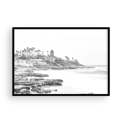 Fine art of WindanSea Beach, La Jolla California horizontal landscape black and white print by Southern California photographer Kim Dybczak of Salt Creek Prints, featuring a powerful waves crashing against the rocky shore of California coast. Beach homes and palm trees sit atop the cliffside, with stairs leading down to a sheltered area. Photograph in minimalist framed mock up