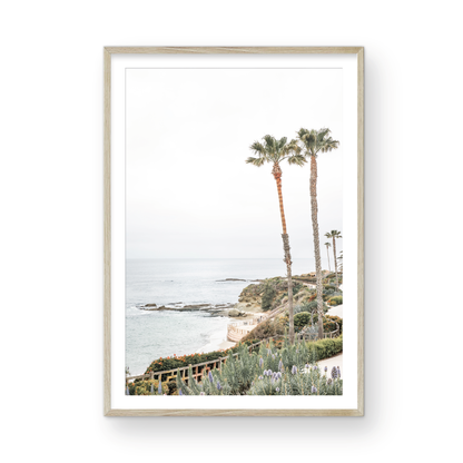 Vertical coastal photography featuring a scenic view of the ocean with palm trees in the background, set against a white sky, located in Laguna California. Photograph in minimalist mock up.