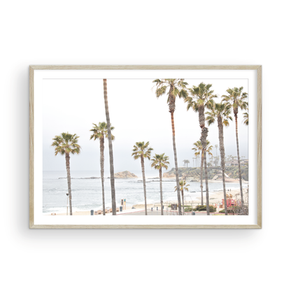 Horizontal coastal photography of a beachscape at Laguna Beach, California, beach art print featuring palm trees and a clear blue sky with a few clouds over a beach scene. Photograph in minimalist mock up.