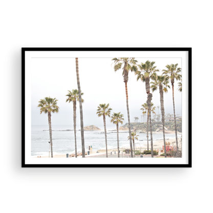 Horizontal coastal photography of a beachscape at Laguna Beach, California, beach art print featuring palm trees and a clear blue sky with a few clouds over a beach scene. Photograph in minimalist mock up.