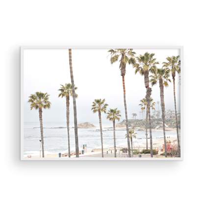 Horizontal coastal photography of a beachscape at Laguna Beach, California, beach art print featuring palm trees and a clear blue sky with a few clouds over a beach scene. Photograph in minimalist mock up.