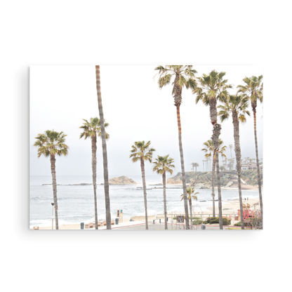 Horizontal coastal photography of a beachscape at Laguna Beach, California, beach art print featuring palm trees and a clear blue sky with a few clouds over a beach scene. Photograph in minimalist mock up.