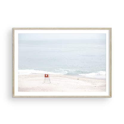 Horizontal coastal photography featuring a red and white lifeguard chair and a calm ocean background, located in Laguna California. Photograph in minimalist mock up.