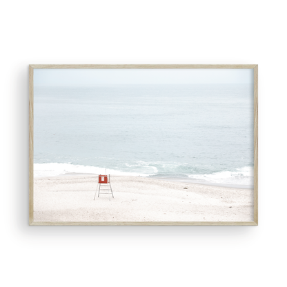 Horizontal coastal photography featuring a red and white lifeguard chair and a calm ocean background, located in Laguna California. Photograph in minimalist mock up.