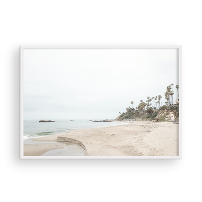 Horizontal coastal photography of a white lifeguard tower at Laguna Beach, California, depicting a beach scene with palm trees and a calm ocean. Photograph in minimalist mock up.