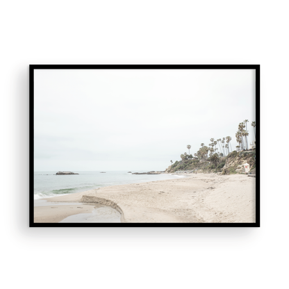 Horizontal coastal photography of a white lifeguard tower at Laguna Beach, California, depicting a beach scene with palm trees and a calm ocean. Photograph in minimalist mock up.