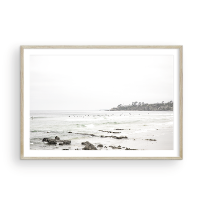 Landscape coastal photography of Salt Creek Beach with dark rocks on the shore and numerous surfers in the ocean. A neutral ocean print perfect for beach house decor. Photograph in minimalist mock up.