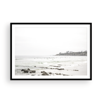 Landscape coastal photography of Salt Creek Beach with dark rocks on the shore and numerous surfers in the ocean. A neutral ocean print perfect for beach house decor. Photograph in minimalist mock up.