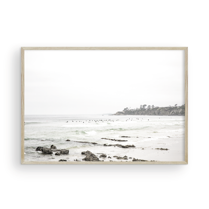 Landscape coastal photography of Salt Creek Beach with dark rocks on the shore and numerous surfers in the ocean. A neutral ocean print perfect for beach house decor. Photograph in minimalist mock up.