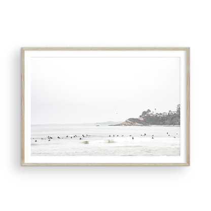 Landscape surf wall decor showing many surfers waiting for waves in the ocean at Salt Creek Beach, with a distant cliffside. This print captures the surf vibes of Southern California. Photograph in minimalist mock up.