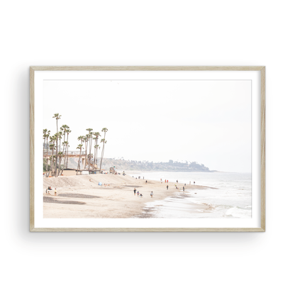 Landscape coastal photography of a wide sandy beach at San Clemente State Beach, with tall palm trees and people enjoying the calm ocean. Perfect for a beach theme wall decor. Photograph in minimalist mock up.