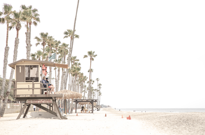 A wide landscape coastal photography view of San Clemente State Beach in Southern California, featuring a row of tall palm trees, a lifeguard tower, and people enjoying the calm beach. This image evokes Summer Vibes Wall Art and tropical beach print aesthetics. 