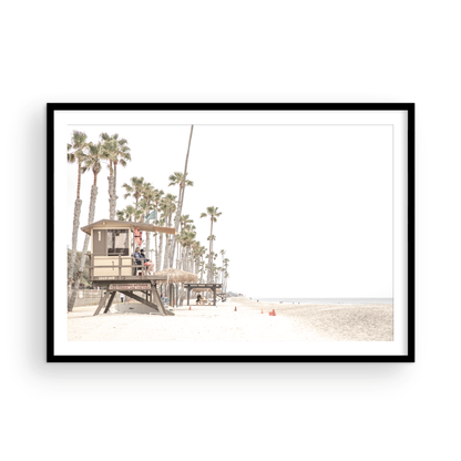 A wide landscape coastal photography view of San Clemente State Beach in Southern California, featuring a row of tall palm trees, a lifeguard tower, and people enjoying the calm beach. This image evokes Summer Vibes Wall Art and tropical beach print aesthetics. Photograph in minimalist mock up.