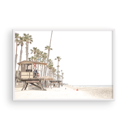 A wide landscape coastal photography view of San Clemente State Beach in Southern California, featuring a row of tall palm trees, a lifeguard tower, and people enjoying the calm beach. This image evokes Summer Vibes Wall Art and tropical beach print aesthetics. Photograph in minimalist mock up.