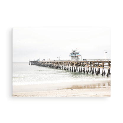 A long wooden pier, the San Clemente Pier, extends into the ocean in this landscape coastal photography. The beach in the foreground suggests a calm ocean print, ideal for a large coastal wall art or a beach cottage wall decor. Photograph in minimalist mock up.