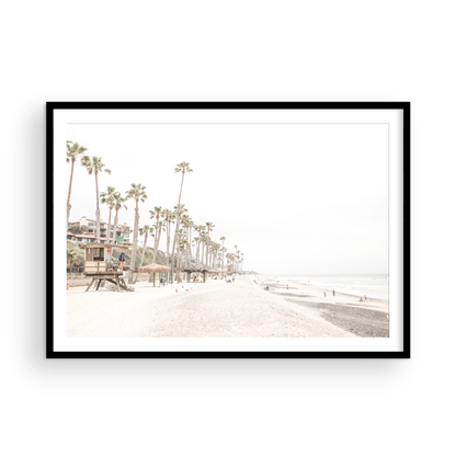 A wide landscape coastal photography view of San Clemente State Beach in Southern California, featuring a row of tall palm trees, a lifeguard tower, and people enjoying the calm beach. This horizontal image evokes Summer Vibes Wall Art and tropical beach print aesthetics. Photograph in minimalist mock up.