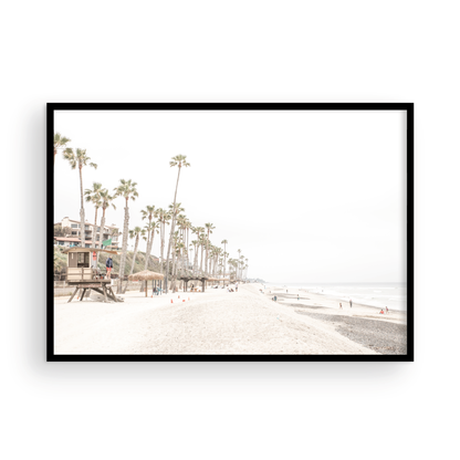 A wide landscape coastal photography view of San Clemente State Beach in Southern California, featuring a row of tall palm trees, a lifeguard tower, and people enjoying the calm beach. This horizontal image evokes Summer Vibes Wall Art and tropical beach print aesthetics. Photograph in minimalist mock up.