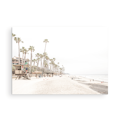 A wide landscape coastal photography view of San Clemente State Beach in Southern California, featuring a row of tall palm trees, a lifeguard tower, and people enjoying the calm beach. This horizontal image evokes Summer Vibes Wall Art and tropical beach print aesthetics. Photograph in minimalist mock up.