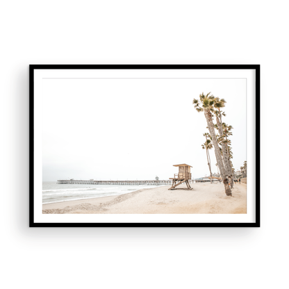 A wide landscape coastal photography view of San Clemente State Beach in Southern California, featuring a row of tall palm trees, a lifeguard tower, and people enjoying the calm beach. This image evokes Summer Vibes Wall Art and tropical beach print aesthetics. Photograph in minimalist mock up.