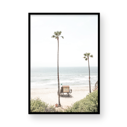 Vertical beach wall art featuring a lifeguard tower nestled between two tall palm trees on a sunny California beach, capturing a serene beach vibe. Photograph in minimalist mock up.