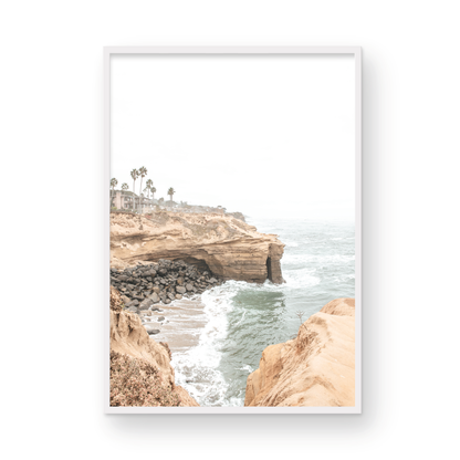 Fine art of Sunset Cliffs, San Diego California vertical print of hazy high-angle landscape beach photography captures a light blue ocean meeting tall tan, rocky, brown cliffs rise as iconic coastal scenery. Photograph in minimalist mock up.