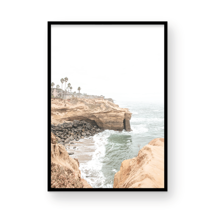 Fine art of Sunset Cliffs, San Diego California vertical print of hazy high-angle landscape beach photography captures a light blue ocean meeting tall tan, rocky, brown cliffs rise as iconic coastal scenery. Photograph in minimalist mock up.