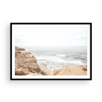 Fine art of Sunset Cliffs, San Diego California horizontal print of hazy high-angle landscape beach photography captures a light blue ocean meeting tall tan and brown cliffs rise as iconic coastal scenery. Photograph in minimalist mock up.