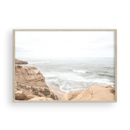 Fine art of Sunset Cliffs, San Diego California horizontal print of hazy high-angle landscape beach photography captures a light blue ocean meeting tall tan and brown cliffs rise as iconic coastal scenery. Photograph in minimalist mock up.
