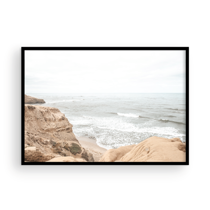 Fine art of Sunset Cliffs, San Diego California horizontal print of hazy high-angle landscape beach photography captures a light blue ocean meeting tall tan and brown cliffs rise as iconic coastal scenery. Photograph in minimalist mock up.