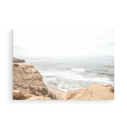 Fine art of Sunset Cliffs, San Diego California horizontal print of hazy high-angle landscape beach photography captures a light blue ocean meeting tall tan and brown cliffs rise as iconic coastal scenery. Photograph in minimalist mock up.