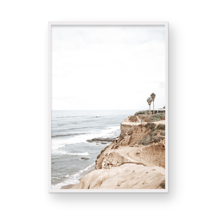 Fine art of Sunset Cliffs, San Diego California vertical print of hazy high-angle landscape beach photography captures a light blue ocean meeting tall tan and brown cliffs rise as iconic coastal scenery. Photograph in minimalist mock up.