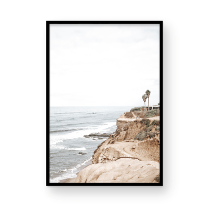 Fine art of Sunset Cliffs, San Diego California vertical print of hazy high-angle landscape beach photography captures a light blue ocean meeting tall tan and brown cliffs rise as iconic coastal scenery. Photograph in minimalist mock up.