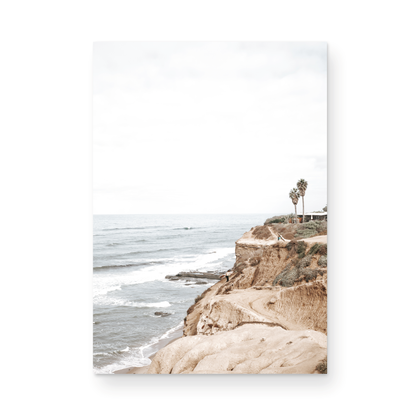Fine art of Sunset Cliffs, San Diego California vertical print of hazy high-angle landscape beach photography captures a light blue ocean meeting tall tan and brown cliffs rise as iconic coastal scenery. Photograph in minimalist mock up.
