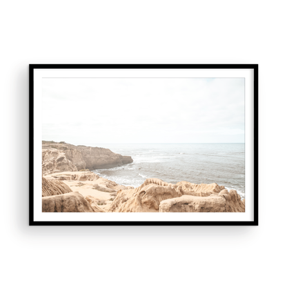 Fine art of Sunset Cliffs, San Diego California horizontal print of hazy high-angle landscape beach photography captures a light blue ocean meeting tall tan and brown cliffs rise as iconic coastal scenery. Photograph in minimalist mock up.