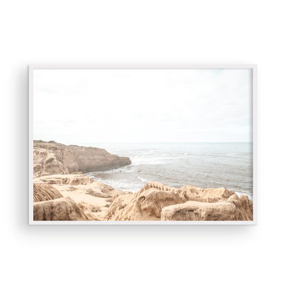 Fine art of Sunset Cliffs, San Diego California horizontal print of hazy high-angle landscape beach photography captures a light blue ocean meeting tall tan and brown cliffs rise as iconic coastal scenery. Photograph in minimalist art mock up.