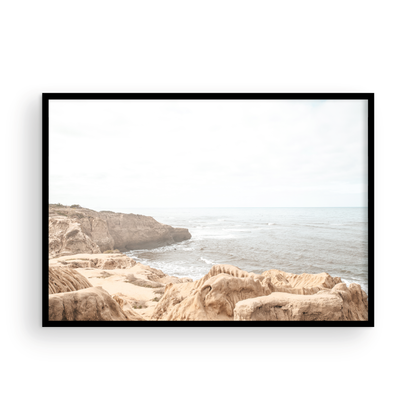Fine art of Sunset Cliffs, San Diego California horizontal print of hazy high-angle landscape beach photography captures a light blue ocean meeting tall tan and brown cliffs rise as iconic coastal scenery. Photograph in minimalist mock up.