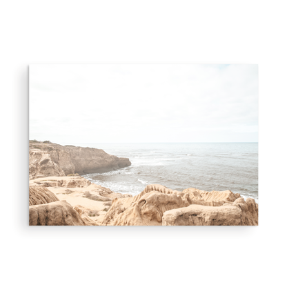Fine art of Sunset Cliffs, San Diego California horizontal print of hazy high-angle landscape beach photography captures a light blue ocean meeting tall tan and brown cliffs rise as iconic coastal scenery. Photograph in minimalist mock up.