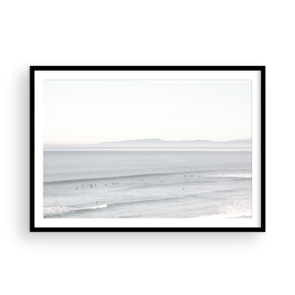 Coastal photography featuring a calm ocean scene with gentle waves and a hazy horizon line, predominantly in blue and white tones. Photograph in minimalist mock up.