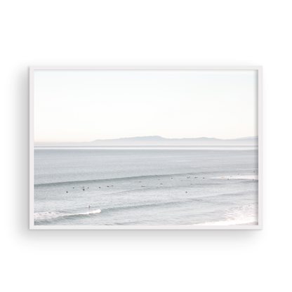 Coastal photography featuring a calm ocean scene with gentle waves and a hazy horizon line, predominantly in blue and white tones. Photograph in minimalist mock up.